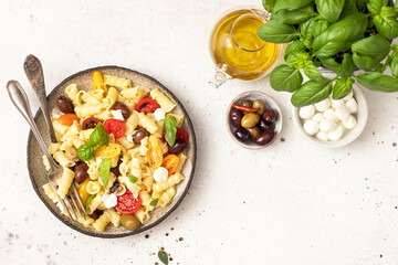 Pasta salad with tomato,  black olives, and cheese mozzarella. Mediterranean cuisine.