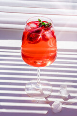 Cooling strawberry Sangria with sparkling wine, strawberry, ice cubes in champagne glass. Refreshing summer alcoholic cocktail drink , lemonade or ice tea. Copy space for text