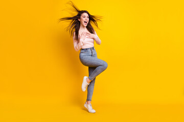 Fototapeta na wymiar Full size photo of young funky smiling amazed girl with flying hair hear unexpected news isolated on yellow color background