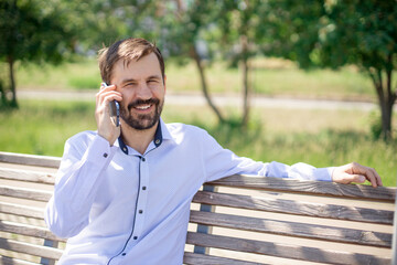 Fototapeta premium smiling men talking on mobile phone in outdoors