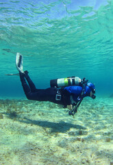 A scuba diver dives from the surface to the bottom. The diver begins his dive underwater. Diver shows balance under water