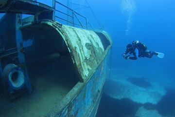 Scuba Divers Exploring underwater ship wreck. Diver discovering the shipwreck sunken at deep sea bottom