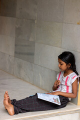girl studying her lessons at home by reading book