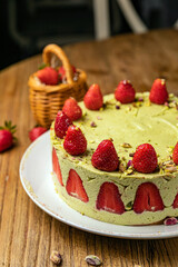 Pistachio cake with strawberries on a wooden table
