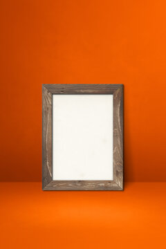 Wooden picture frame leaning on an orange wall