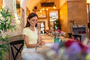 Happy woman in cafe talking on phone. Attractive woman sitting in a cafe with a cell phone.