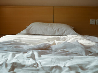 Unmade bed with crumpled duvet, bed sheet and pillow
