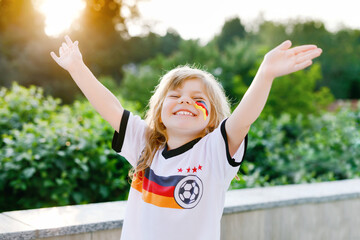 Little blond preschool girl watching soccer football cup game on public viewing. Happy joyful...