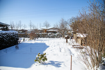 A snow-covered allotment garden rests in winter