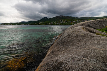 bay in the fjord, clear water, rocky coast. Mountains on the horizon