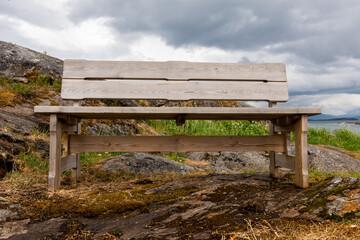 bench by the sea bay in the fjord, clear water rocky coast. Mountains on the horizon