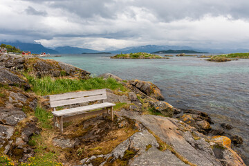 bench by the sea bay in the fjord, clear water rocky coast. Mountains on the horizon