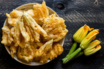 Fried zucchini flowers in batter on wooden background