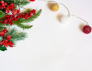 Christmas background, spruce twigs with red berries and a garland with balloons on a white background, flat lay, copy space