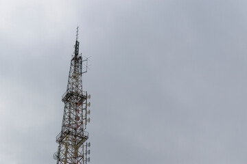 Telecommunication tower. Metal constructions. Transmitting antennas. The background is a cloudy sky.