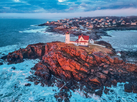 Aerial drone image of The Nubble Lighthouse on its rocky island ion a winter morning sunrise