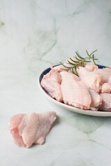 Raw chicken wings with herbs, over a blue plate, green background