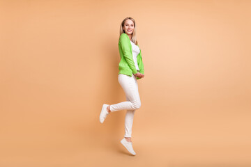 Fototapeta na wymiar Full length body size profile side view of attractive cheerful girl jumping having fun isolated over beige pastel color background