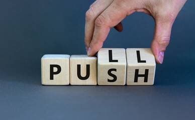 Pull or push symbol. Businessman turns wooden cubes and changes the word 'push' to 'pull'. Beautiful grey background, copy space. Business and pull or push concept. - obrazy, fototapety, plakaty