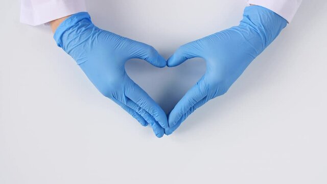 Doctor's Hands In Medical Gloves Making Shape Of Heart On White Background With Copy Space. High Quality 4k Footage