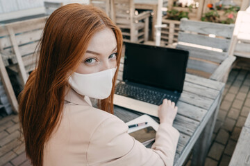 Outdoor work areas, workplace. Take office Outside, Work Moves Outdoors During Pandemic. Mobility, autonomy, work remotely. Redhead business woman working at laptop outdoors