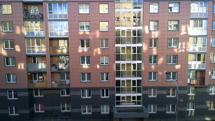 New residential building exterior with reflection of sun rays. Rising prices for purchase, sale and rental of real estate. Property. Inexpensive apartments. Comfortable housing. Cityscape.  Windows.