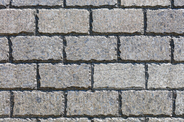 The beautiful texture of the wall is lined with polished stone tiles with chopped edges along the perimeter, illuminated by sunlight.