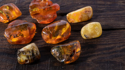Beautiful Baltic amber stones different in color and shape on a wooden background. Amber texture, material for jewelers, ancient healing mineral.