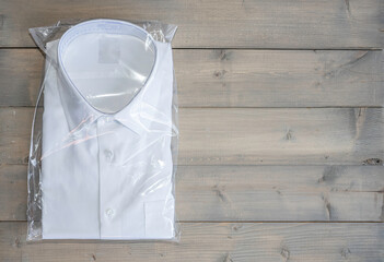 White shirt folding in the package on wooden background.