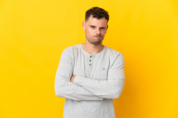 Young caucasian handsome man isolated on yellow background feeling upset