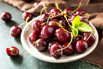 Ripe organic berry. Fresh Red sweet cherry on plate on a dark stone tabletop.