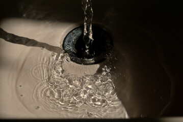 fregadero de baño, contraluz y luz de mañana, agua corriendo gotas, reflejos