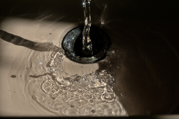 fregadero de baño, contraluz y luz de mañana, agua corriendo gotas, reflejos