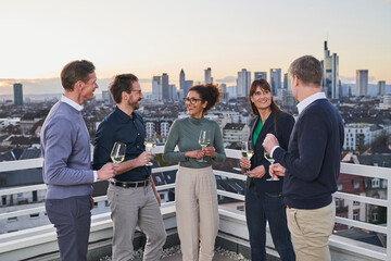 Smiling entrepreneurs with wine glasses standing on building terrace