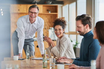 Cheerful male and female entrepreneurs with colleagues in board room