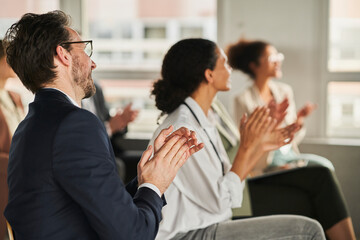 Businessman clapping hands with colleagues in conference event
