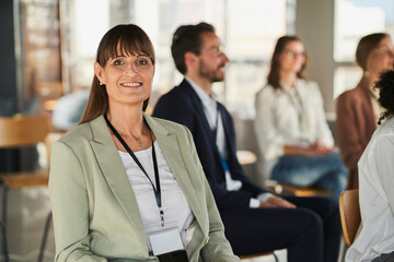 Smiling businesswoman sitting with colleagues at educational event in office