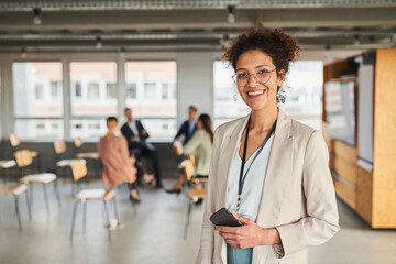 Smiling businesswoman with mobile phone at conference centre