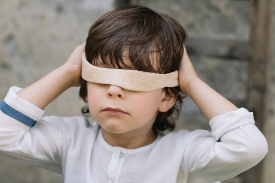 Innocent boy covering eyes with dough while playing at back yard