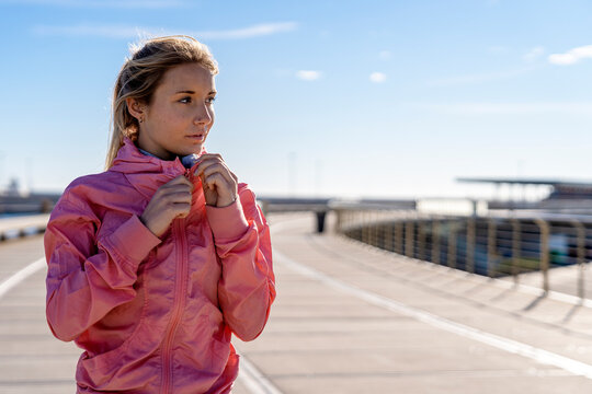 Thoughtful woman holding jacket zipper while looking away