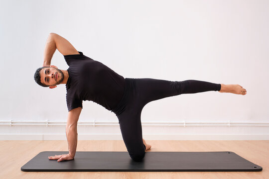 Mid adult man stretching on mat in exercise room
