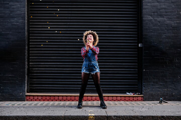 Happy woman playing with party popper on footpath