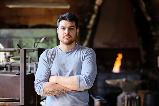 Confident male blacksmith standing with arms crossed at workshop - Powered by Adobe