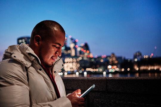 Young man using smart phone in city at night