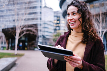 Smiling female professional holding digital tablet while looking away