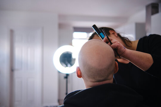 Female make-up artist doing makeup of bald male model in studio