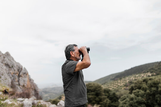 Man looking at view through binoculars on mountain