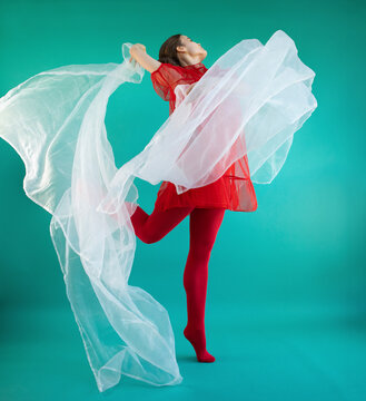 Young female dancer dancing against turquoise background