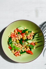 Vegetable salad of cucumbers and tomatoes with chickpeas in a green plate close-up