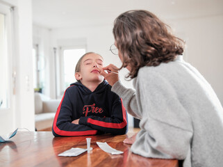 Mature woman doing daughter's covid-19 test at home